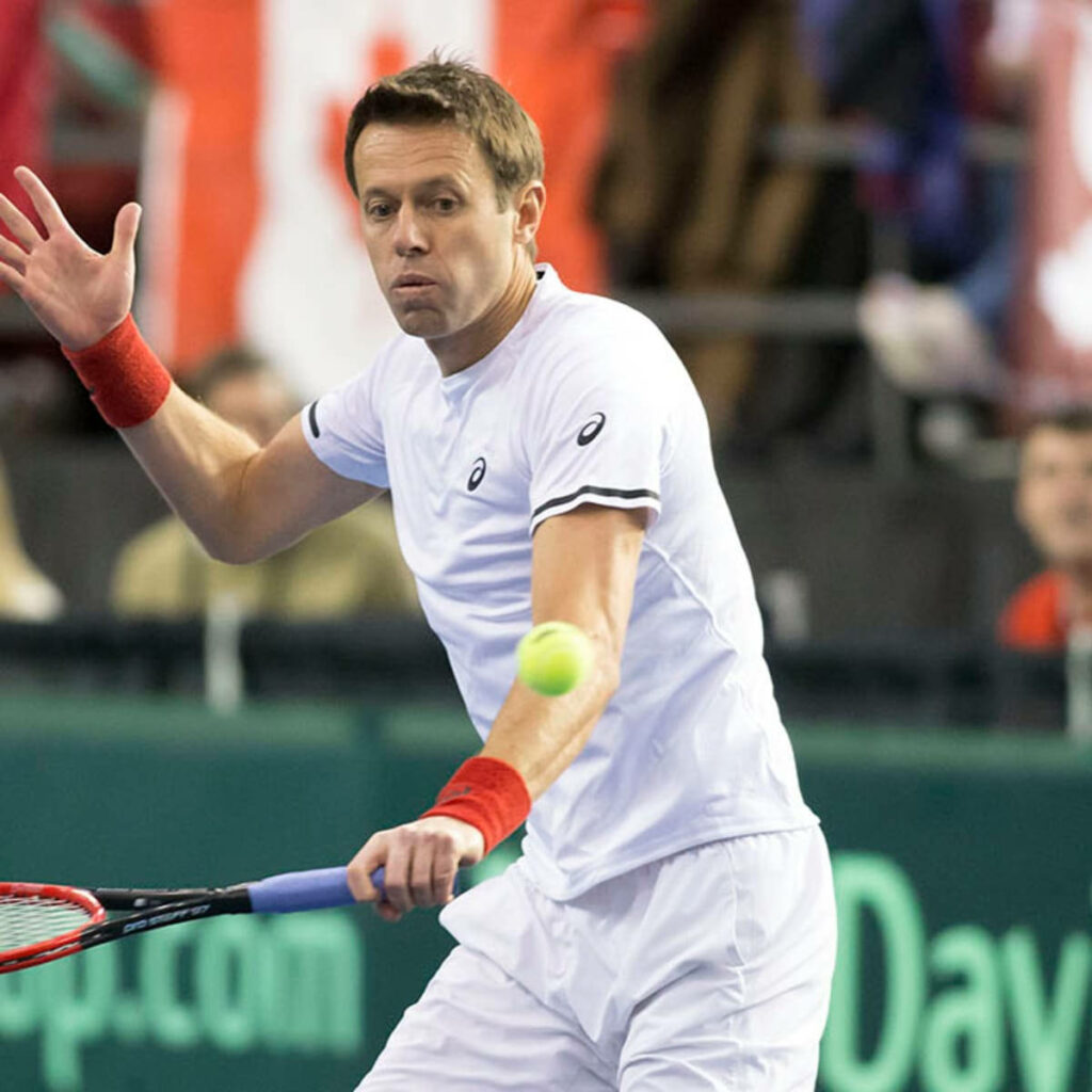 Daniel Nestor tennis player mid-match returning shot in white attire vibrant sports wallpaper background
