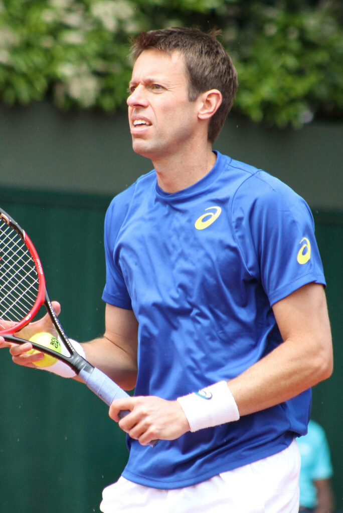 Daniel Nestor focused on court in blue shirt holding racquet green outdoor tennis wallpaper background