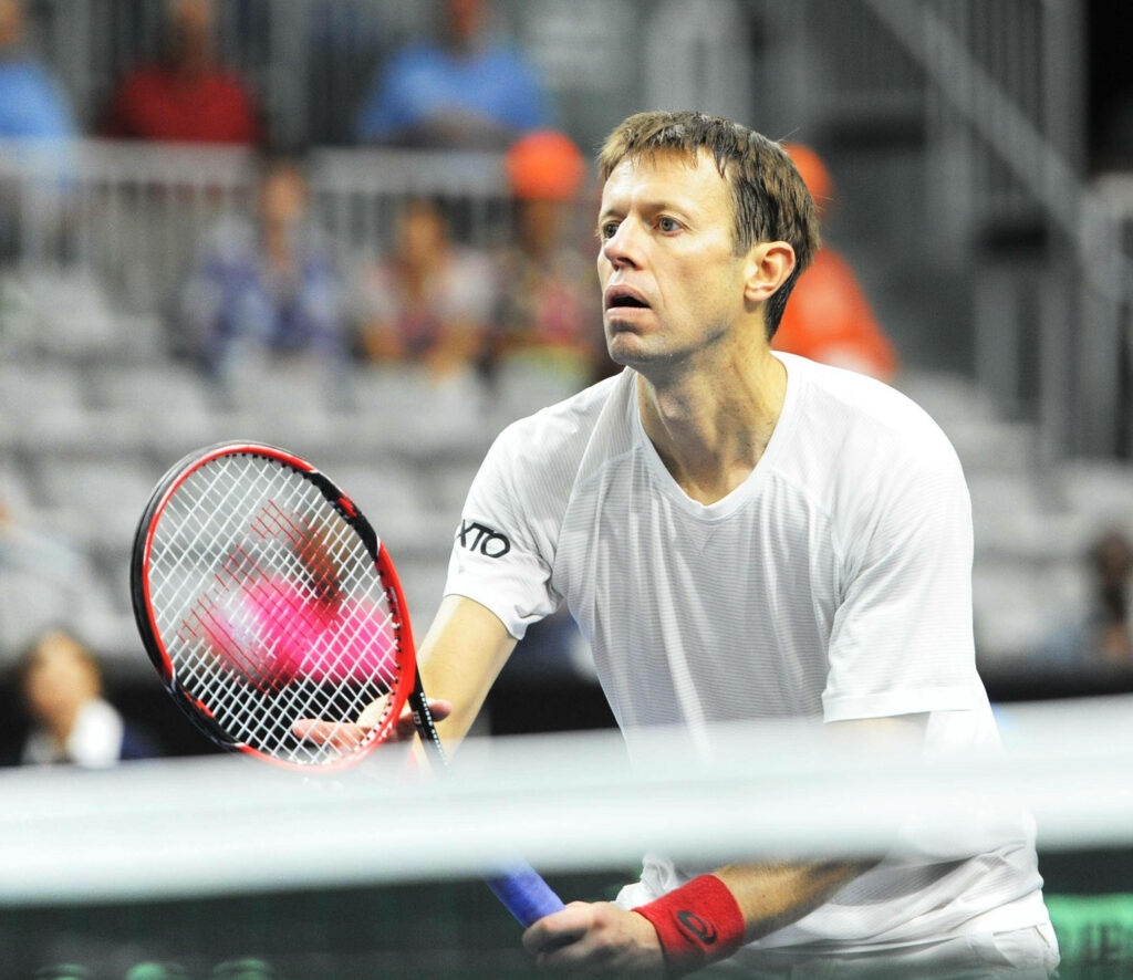 Canadian tennis pro Daniel Nestor focused mid-match holding racquet in white outfit on court Wallpaper