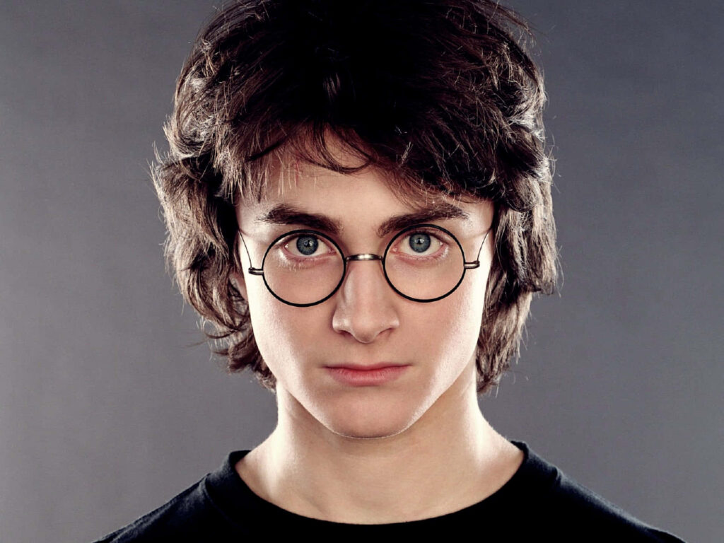 Daniel Radcliffe close-up portrait with iconic round glasses and tousled hair on gray background Wallpaper