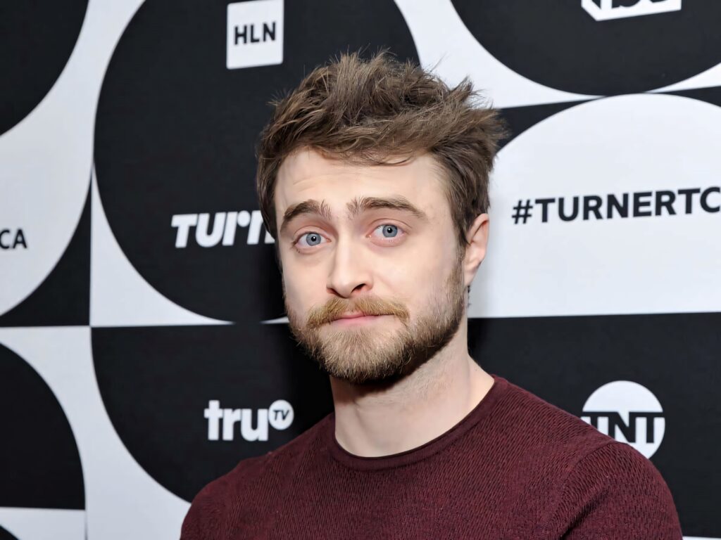 Daniel Radcliffe in maroon sweater poses against black and white geometric modern backdrop portrait Wallpaper