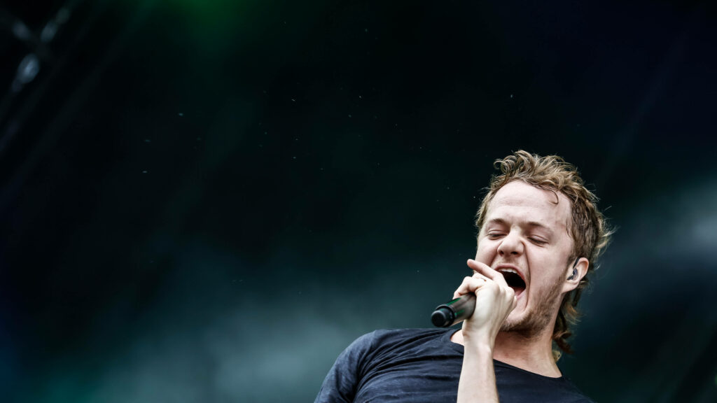 Daniel Reynolds Imagine Dragons lead singer passionately performing on stage with microphone Wallpaper