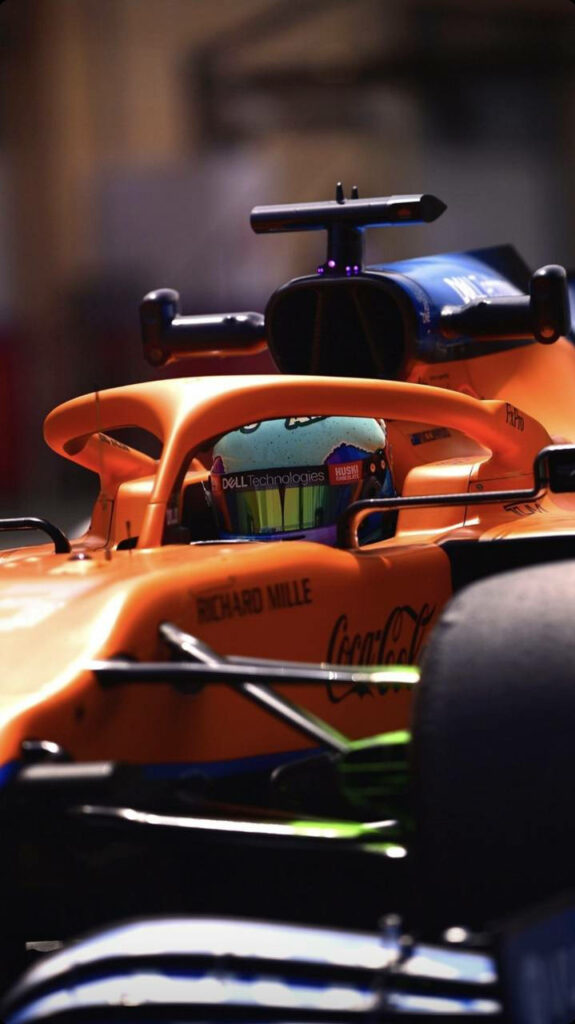 Close-up of Formula 1 racer Daniel Ricciardo focused inside vibrant orange F1 car motorsport wallpaper