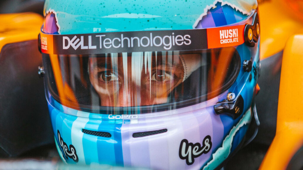 Daniel Ricciardo closeup wearing vibrant blue and orange racing helmet with sponsor logos Wallpaper