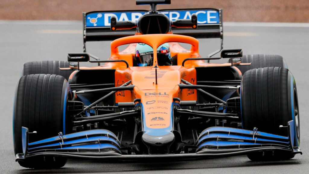 Daniel Ricciardo focused in vibrant orange and blue F1 car racing on track wallpaper background