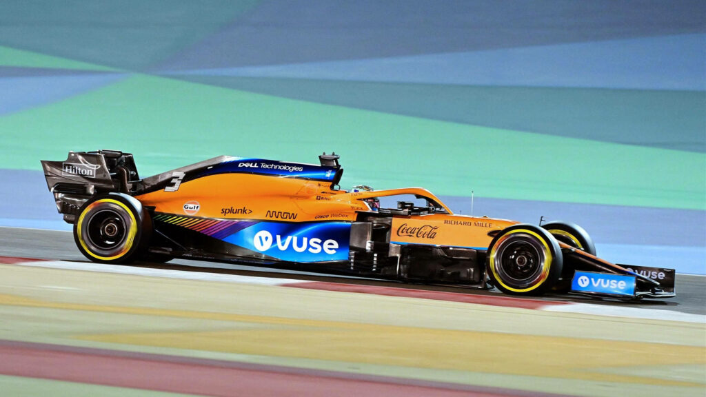 Side view of Daniel Ricciardo McLaren F1 car racing with vibrant orange blue livery on track Wallpaper