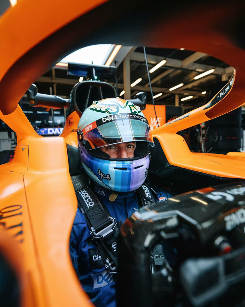 Daniel Ricciardo smiling in bright orange Formula 1 car with detailed race suit and cockpit Wallpaper