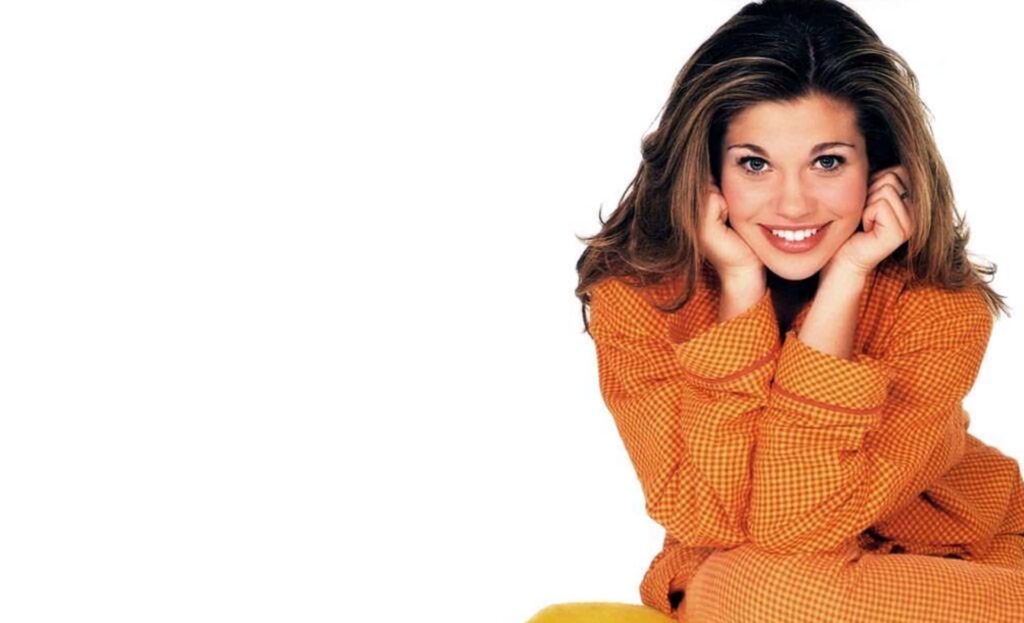 Danielle Fishel in orange checkered outfit smiling brightly on white background vibrant wallpaper