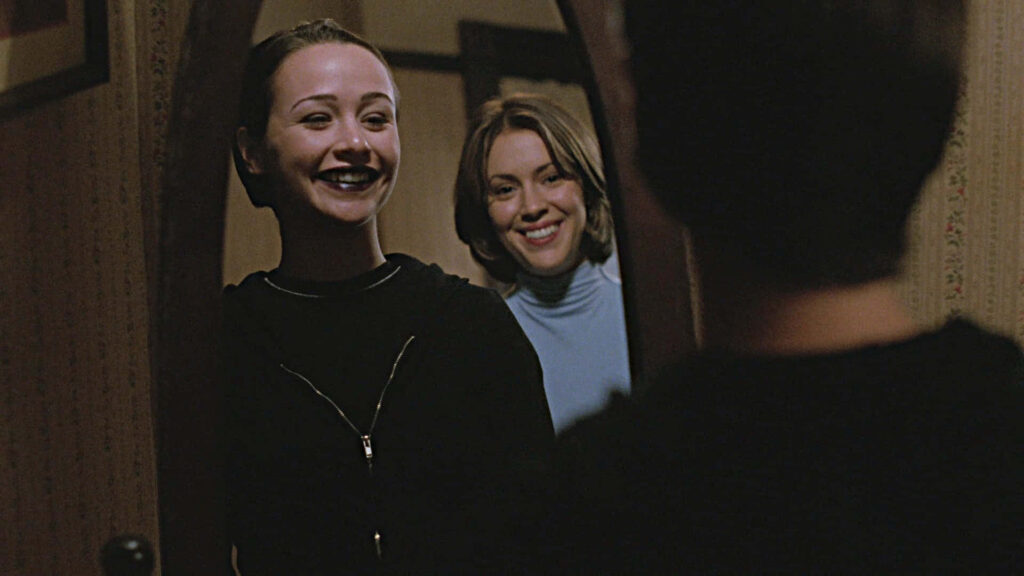 Danielle Harris smiling warmly in front of mirror with friend in cozy vintage style room wallpaper