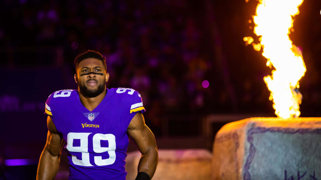 Danielle Hunter in Minnesota Vikings uniform with fiery background and bold purple gold tones Wallpaper