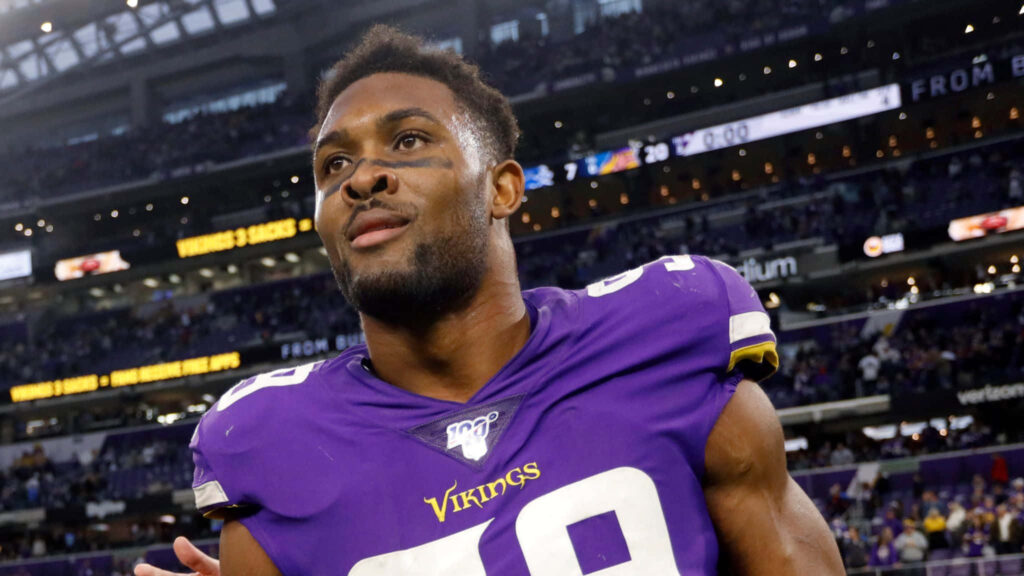 Danielle Hunter Minnesota Vikings in purple gold uniform on field vibrant packed stadium background Wallpaper