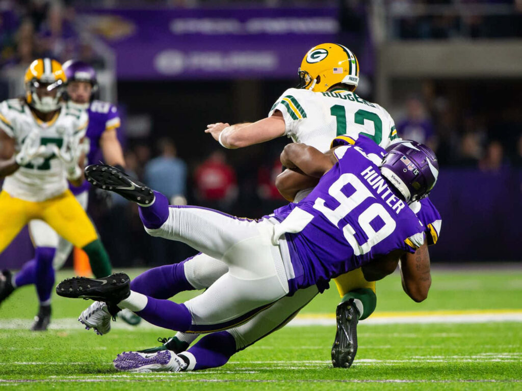 Danielle Hunter sacks Aaron Rodgers in intense Vikings vs Packers NFL game with vibrant team colors Wallpaper