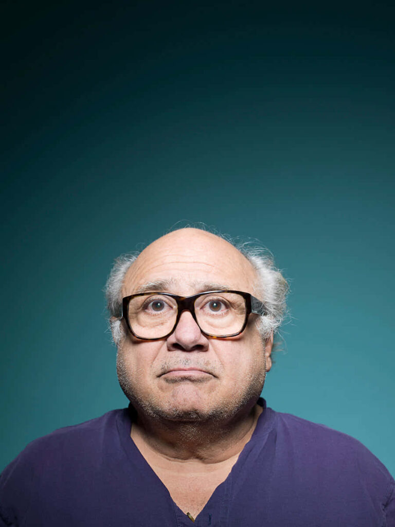 Danny DeVito portrait wallpaper with teal gradient background featuring expressive face and glasses