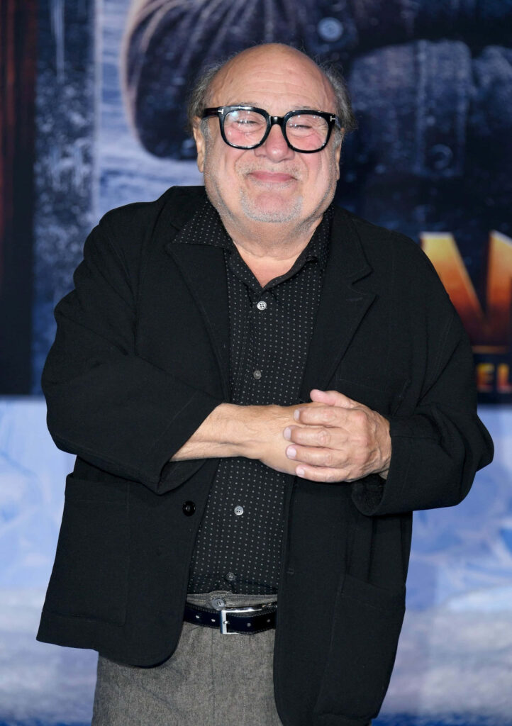 Danny Devito portrait in black jacket patterned shirt cheerful expression cinematic backdrop wallpaper