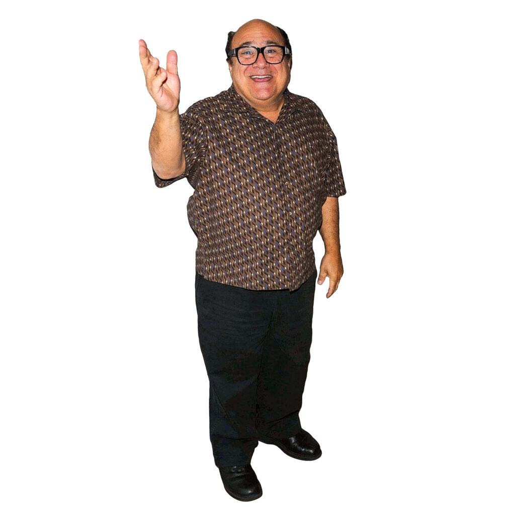 Danny Devito smiling in patterned shirt and dark pants on plain white background wallpaper
