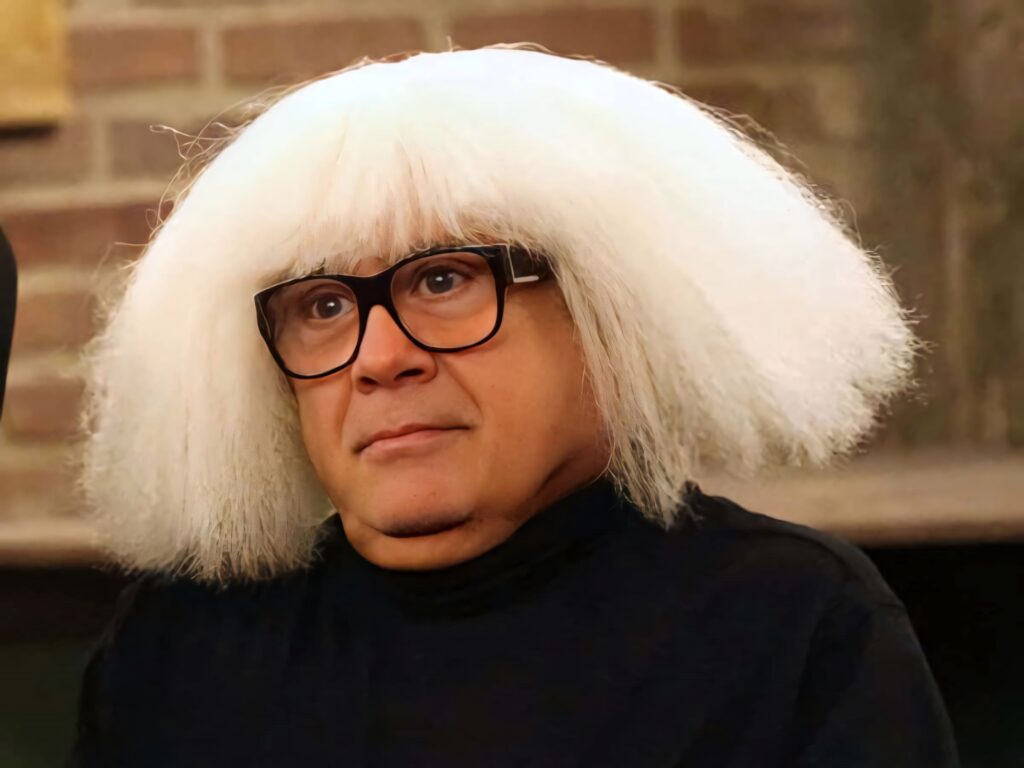 Danny Devito wallpaper with dramatic white wig dark glasses cozy warm background quirky style