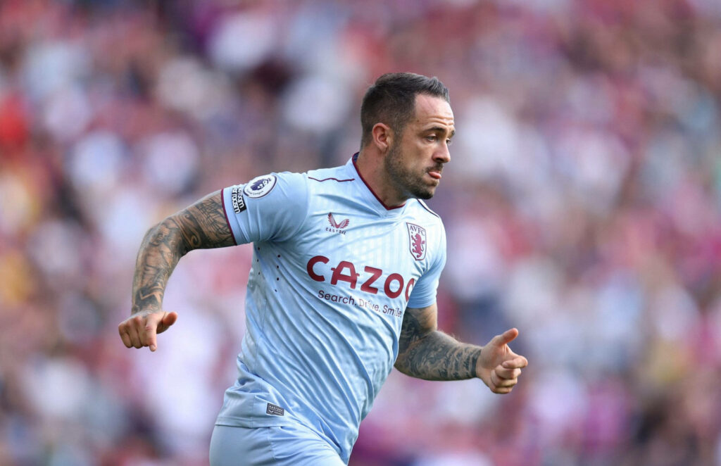 Danny Ings running in Aston Villa kit showing focus athleticism and tattoos on blurred stadium background Wallpaper