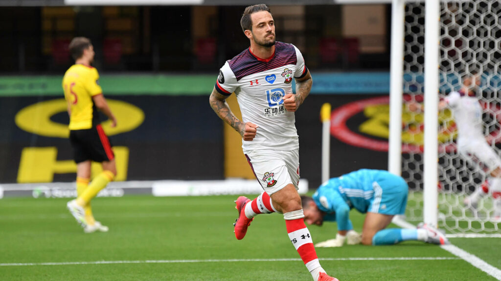 Danny Ings celebrating a goal on green pitch with defeated goalkeeper Premier League football energy Wallpaper
