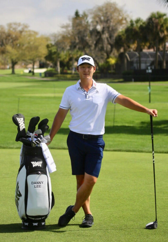 Danny Lee on green golf course in white PXG cap navy shorts leaning on golf bag with driver Wallpaper
