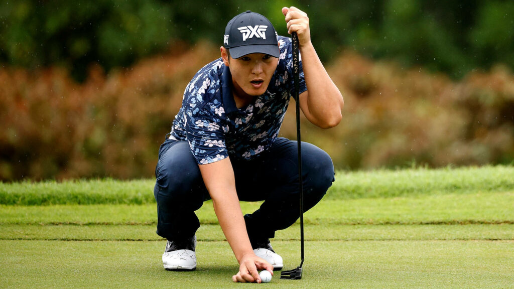 Danny Lee focused lining up putt on lush green golf course wearing floral shirt and PXG cap Wallpaper