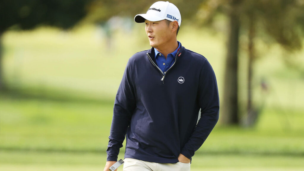 Danny Lee focused on lush golf course wearing navy sweater white cap professional athlete wallpaper