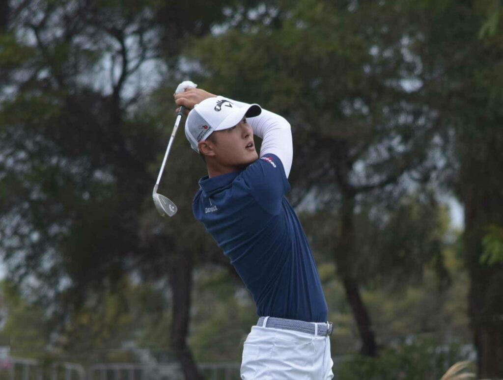 Danny Lee mid-swing on lush golf course focused athletic form with soft green blue background Wallpaper
