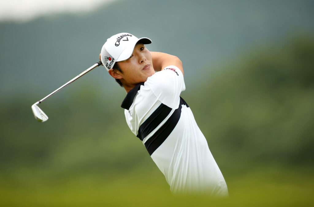 Professional golfer Danny Lee mid-swing on golf course focused athletic form green background wallpaper