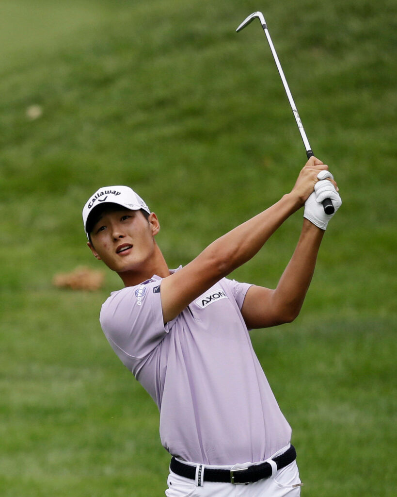 Danny Lee mid-swing on green golf course wearing lavender polo and white cap professional golfer Wallpaper