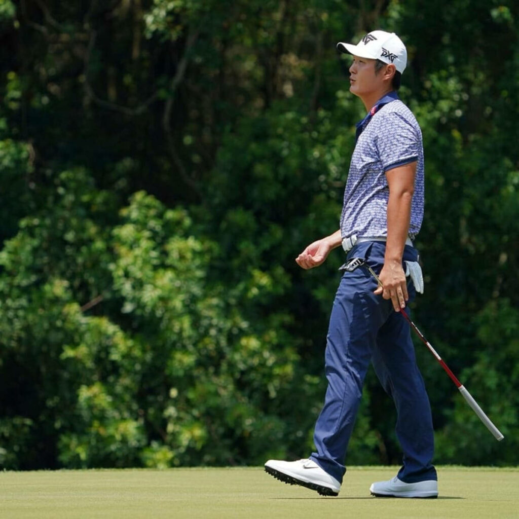 Professional golfer Danny Lee walking on green golf course in blue shirt with putter in hand Wallpaper