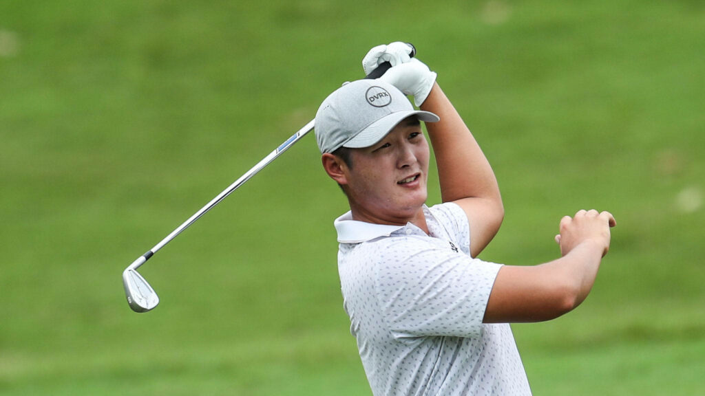 Danny Lee mid golf swing on lush green course wearing grey cap and patterned polo shirt Wallpaper