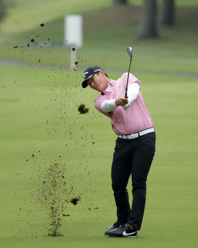 Danny Lee mid-swing on lush golf course in pink shirt and black cap with flying turf action Wallpaper