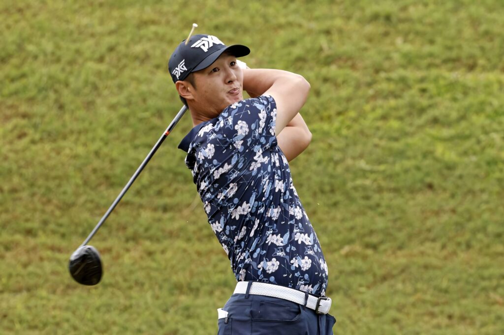 Danny Lee mid-swing on green golf course wearing patterned navy shirt and PXG cap wallpaper
