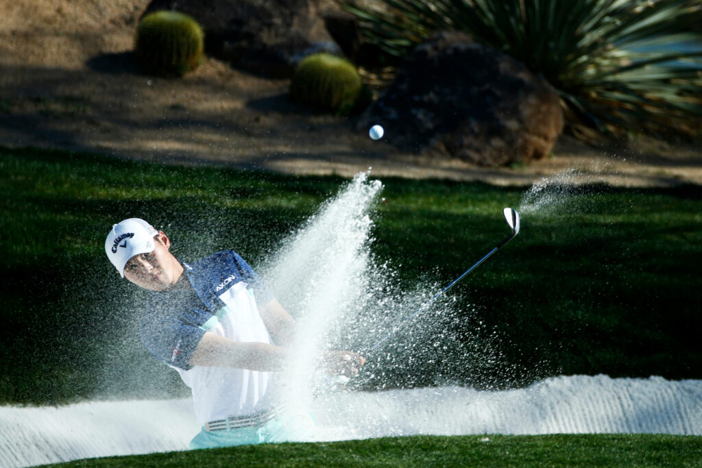 Danny Lee hitting powerful golf bunker shot with sand spray vibrant green grass desert background Wallpaper