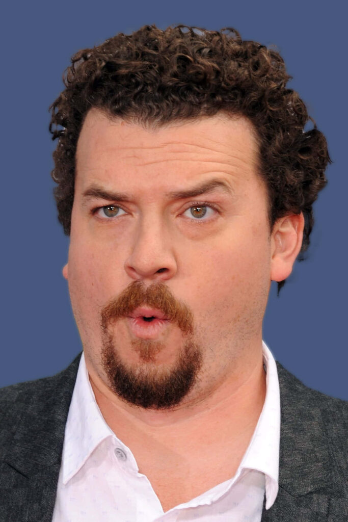 Danny McBride portrait with curly hair and goatee on solid blue background wallpaper