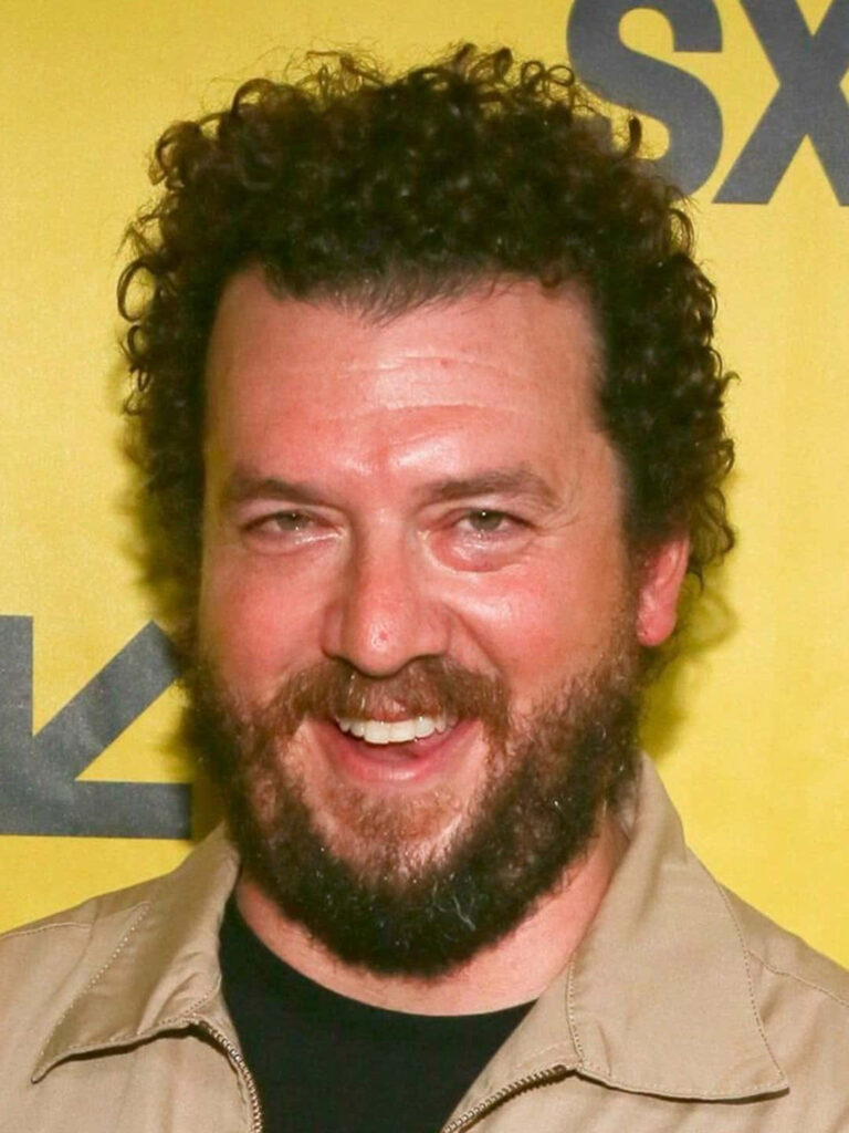 Danny McBride portrait with curly hair full beard friendly smile on vibrant yellow background wallpaper