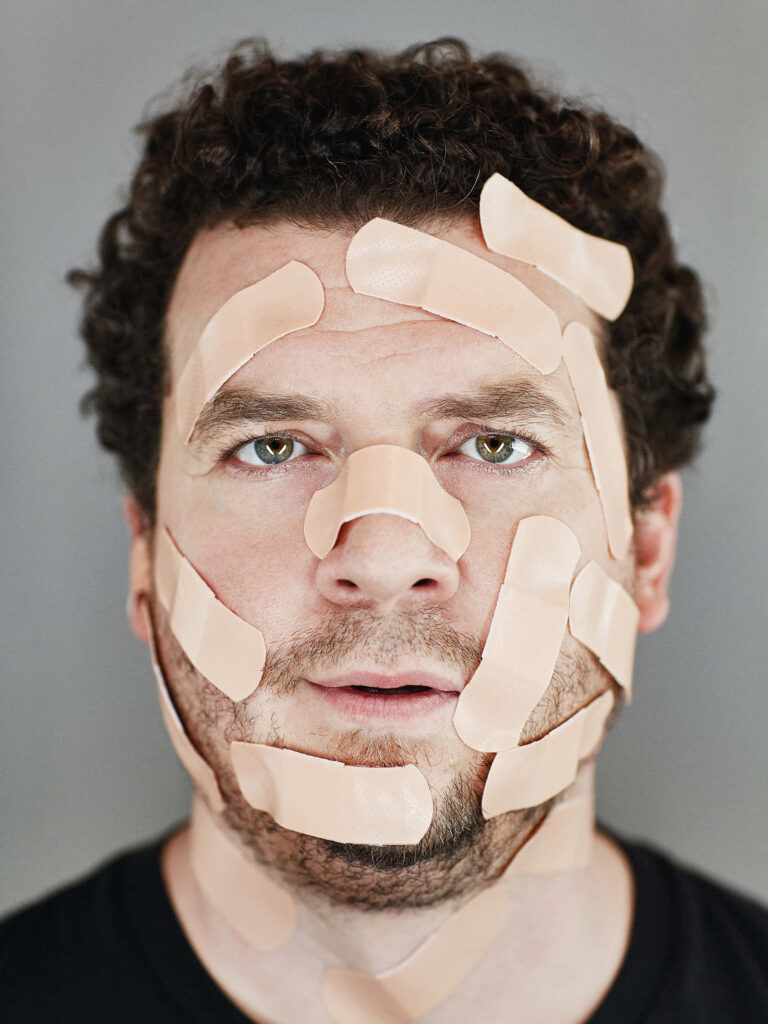 Danny McBride portrait with beige bandages soft lighting neutral background quirky humor wallpaper