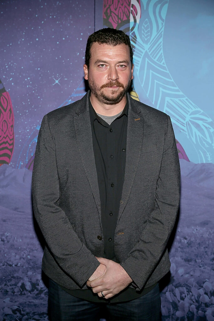 Danny McBride in neutral suit against vibrant purple blue abstract art wallpaper background