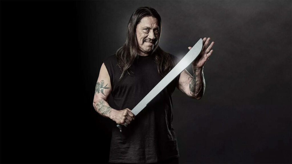 Danny Trejo intense pose with silver machete tattooed arms black outfit dark cinematic background Wallpaper