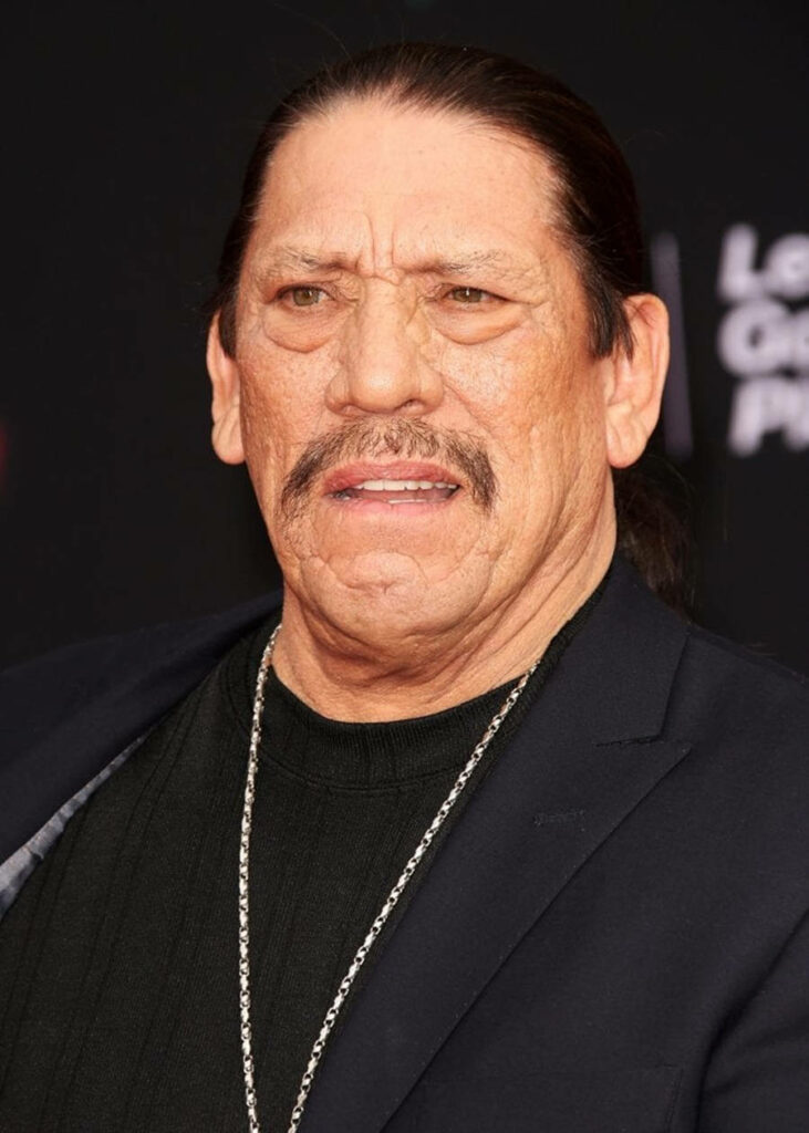 Danny Trejo intense portrait with mustache black outfit silver chain dark cinematic background wallpaper