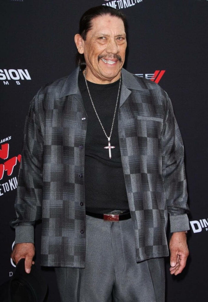 Danny Trejo in gray black check pattern suit with cross necklace and slicked-back hair wallpaper background
