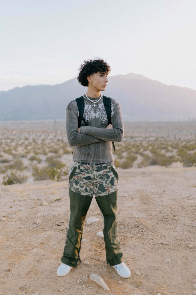 DannyLux in sunlit desert with mountains casual layered clothes backpack calm natural light wallpaper