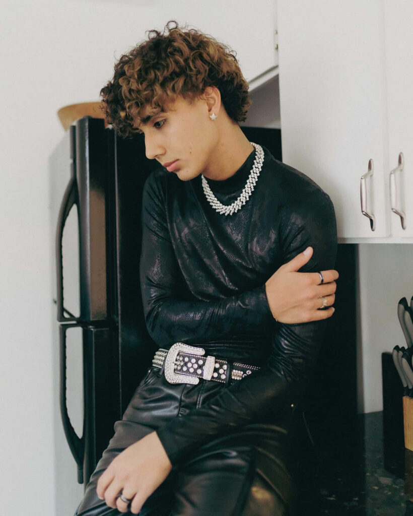DannyLux in sleek black outfit posing in modern kitchen with natural light and stylish accessories Wallpaper