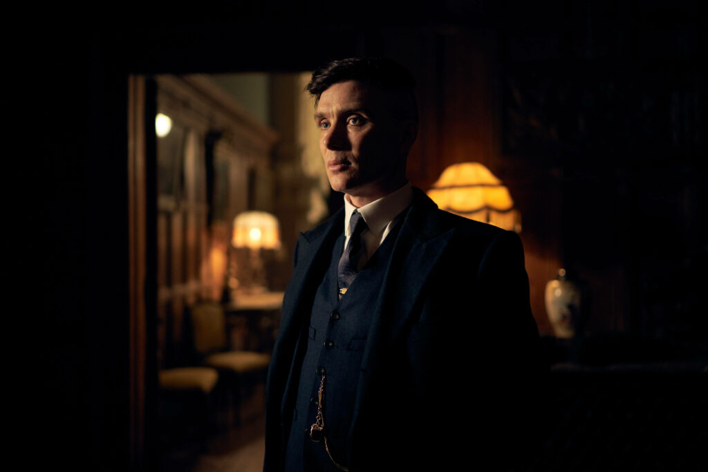 Dapper Detective: Tommy Shelby's Stylish Blue Suit in a Peaky Blinders 8k Background Wallpaper