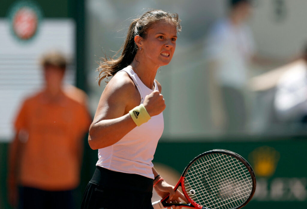 Daria Kasatkina mid-cheer on vibrant tennis court showing determination with racket and clenched fist Wallpaper
