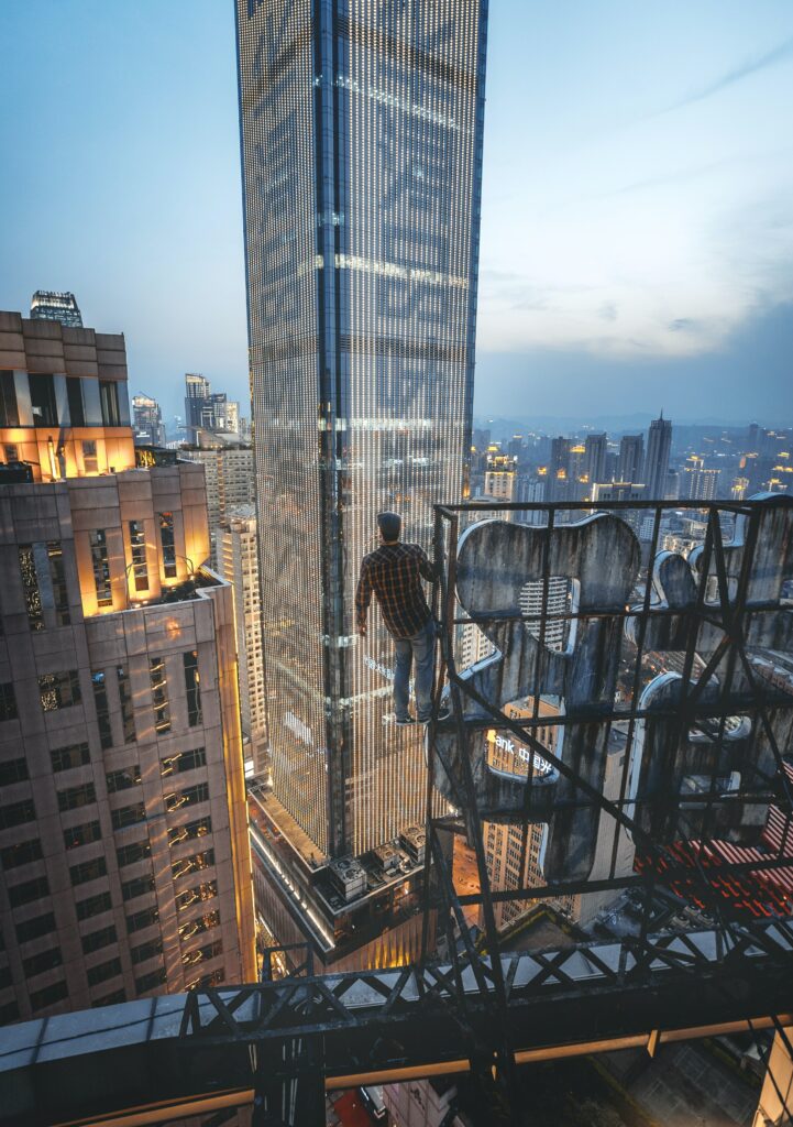 Daring Man on Steel Structure: Thrilling Urban Exploration Wallpaper