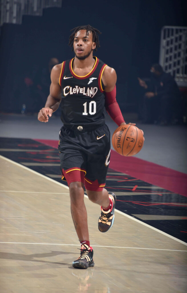Darius Garland dribbling basketball focused intense in black wine Cavaliers jersey dynamic lighting Wallpaper