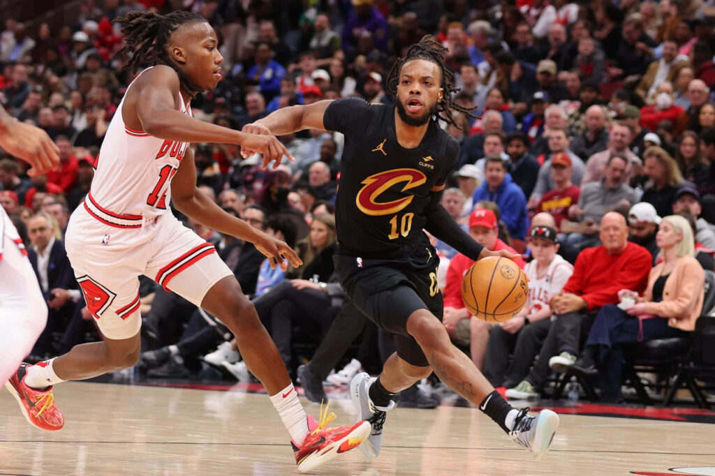 Darius Garland drives past defender in Cleveland Cavaliers black uniform during intense basketball game Wallpaper
