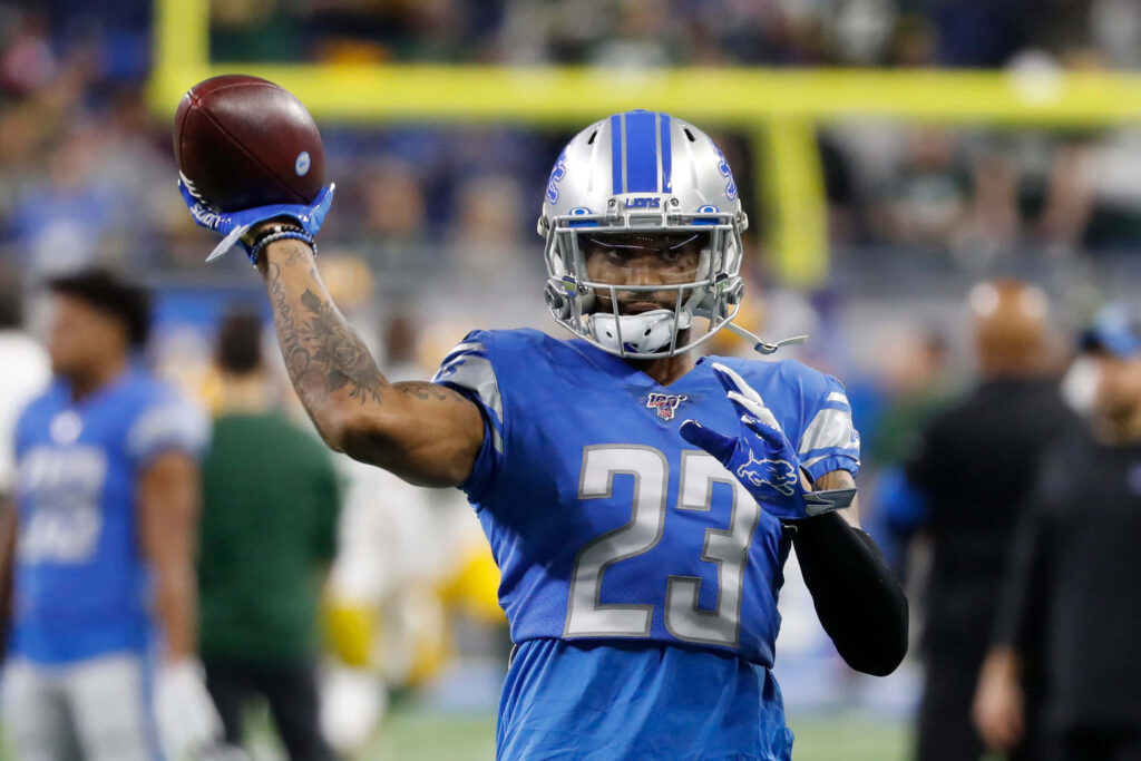 Darius Slay throwing football in blue Detroit Lions uniform showing focus and athleticism Wallpaper