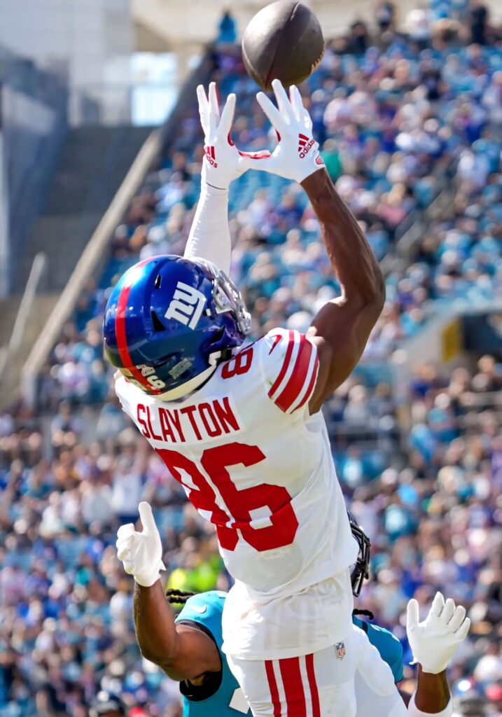 Darius Slayton jumping high to catch football in vibrant sunlit stadium action wallpaper background