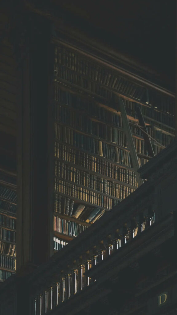 Dark academia wallpaper with vintage books on grand shelves dimly lit for moody library vibes